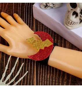 Detail of red crescent moon and gold sequined bat Halloween snap bracelet on hand