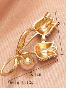 Detailansicht einer goldenen Tulpenbrosche mit Perlen und Strass auf pfirsichfarbener Seide