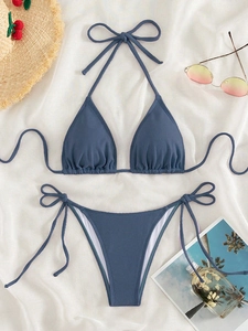 Blue ribbed bikini set with tie-side bottoms on tropical beach holiday background