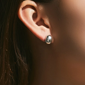 Irregular 925 sterling silver bean stud earrings with a mirrored metallic finish on ear