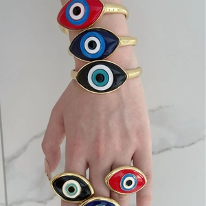 Detail view of colorful evil eye enamel bracelets and rings worn on a hand model