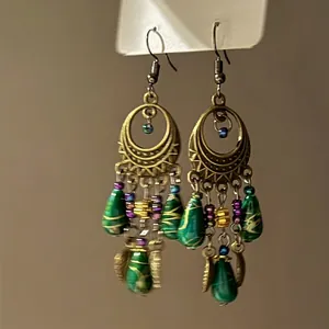 Detailed macro view of bohemian bronze crescent earrings with green teardrop tassels