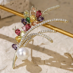 Detail of a golden zircon wheat ear brooch with colorful gems and a large pearl