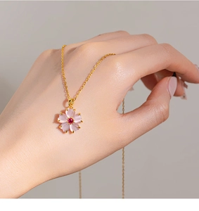 Detailed close-up of a pink cherry blossom pendant necklace in a hand-held view