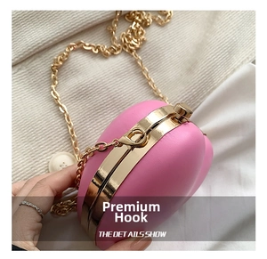Detail of high-quality gold hook and chain on pink heart-shaped leather crossbody bag