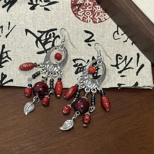 Detail of vintage ethnic drop earrings with antique silver leaf pendants and colored beads