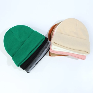 Flat lay of ribbed knit beanies in multiple colors including green black and pink