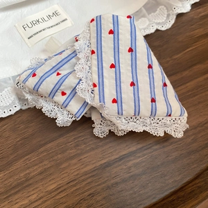 Macro shot of cotton fabric with red heart, blue stripes, and delicate lace trim