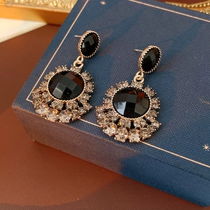 Détail des boucles d'oreilles vintage avec pierres noires et accents de diamants