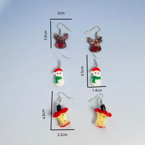 Detailed view of festive Christmas earrings featuring elk, snowman, and apple core shapes