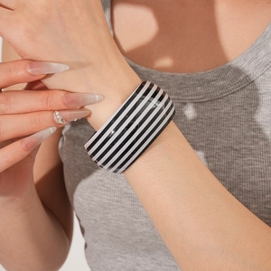 Detail of a bold black and white striped wide bangle worn on a model's wrist