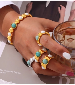 Close-up of gold titanium steel jewelry set with green and white natural stones