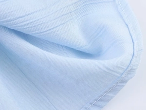 Detailed macro view of light blue lace embroidery fabric with soft cotton texture