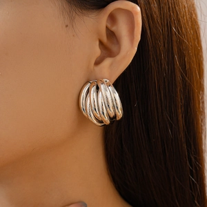 Close-up of multilayer silver twist earrings with a metallic finish on a female model