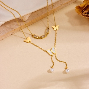 Detail of gold layered necklace featuring butterfly charms and dangling pearls