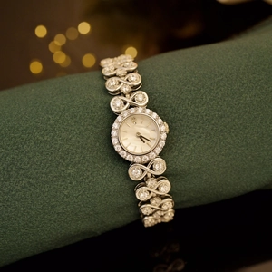 Detail of luxury silver watch with diamond bezel and infinity knot metal bracelet