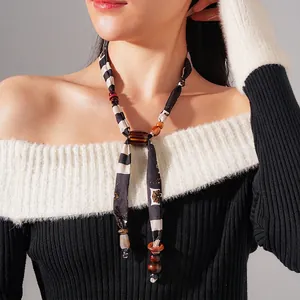 Minimalist fabric silk necklace with wooden beads and resin pendant on a black sweater