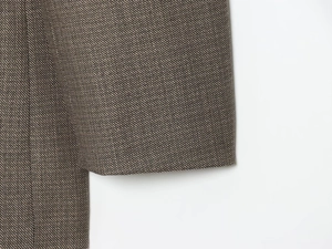 Detailed close-up of premium tweed blazer cuff showing grey twill fabric texture and stitching