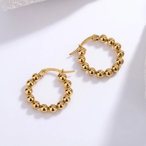 Detail of gold beaded hoop earrings with polished spheres and safe clasp closure