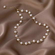 Close-up of vintage freshwater pearl necklace on satin fabric with 14k gold-plated Cuban links