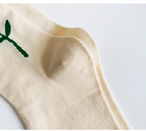 Close-up of beige cotton sock featuring detailed green plant embroidery on the heel area