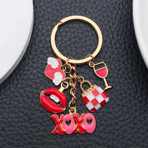 Golden keychain with red lips, wine glass, and heart pendants on black leather