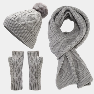 Flat lay of gray cable knit winter set including pompom hat scarf and fingerless gloves