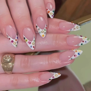 French tip almond nails with colorful rhinestones and gold star nail art charms