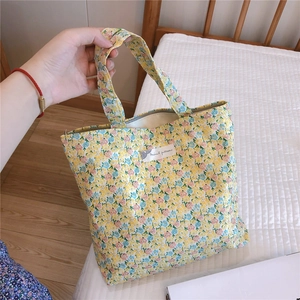 Détail du sac cabas en coton jaune à fleurs avec étiquette en tissu minimaliste