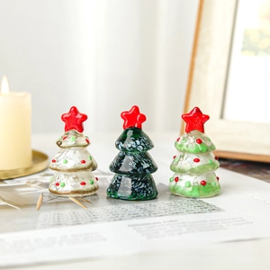 Close-up of three handmade colorful glass Christmas trees with red star toppers
