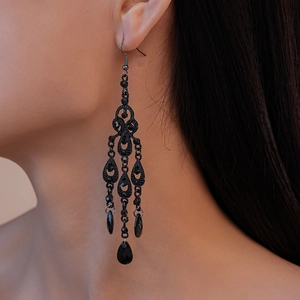 Macro view of gothic black filigree drop earrings with crystals and beaded tassels