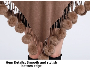 Detail of V-shaped hem featuring faux fur pom-poms and fine tassels on dark brown knit poncho