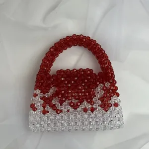 Detailed top view of handmade beaded handbag with red and clear acrylic beads on silk