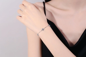 Detail of s925 silver four-leaf clover bracelet with sparkling Moissanite stones on wrist