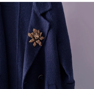 Vintage bronze flower brooch with rhinestone petals pinned on a navy wool coat