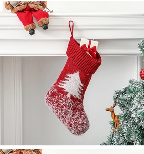 Close-up of red knitted Christmas stocking with white tree pattern on fireplace