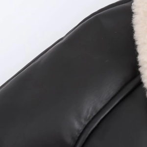 Close-up detail of black leather texture with contrasting beige faux fur lining and stitching