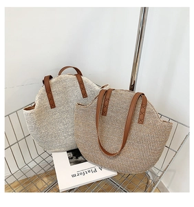 Close-up of woven straw tote bags in beige and khaki with durable brown leather handles