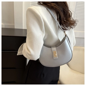 Détail du sac hobo gris clair avec fermoir doré porté à l'épaule par un mannequin