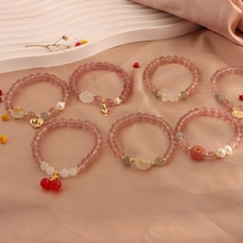 Detailed close-up of pink quartz beaded bracelets with cherry and rabbit gold charms