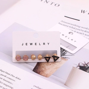 Macro detail of three-pair earring set featuring pink, gold, and black geometric studs
