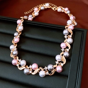 Detail of necklace with gold leaf design featuring pink and grey pearls and crystals