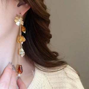 Détail de boucles d'oreilles fleurs à pompons avec perles d'ambre sur le mannequin