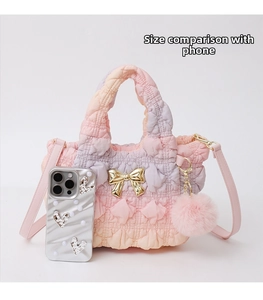 Quilted gradient nylon handbag detail with gold bow decoration and phone for size reference