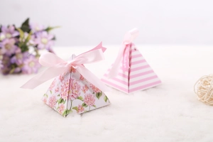 Detail of pink hydrangea and striped pyramid favor boxes with ribbons on white fur