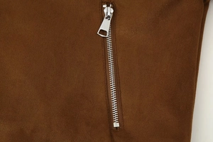Close-up of a silver metal zipper and soft brown suede texture on a cropped jacket