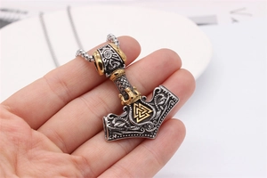 Macro shot of Viking Thor's Hammer pendant with vintage silver finish and golden crown detail
