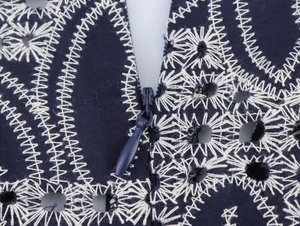 Detailansicht der weißen Stickerei und des verdeckten Reißverschlusses am blauen Kleid