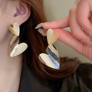 Detail of two-tone heart drop earrings featuring matte gold and mirror silver finishes