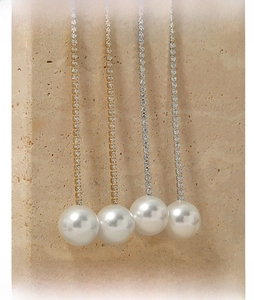 Detail of long tassel earrings with sparkling crystals and large white pearls on stone